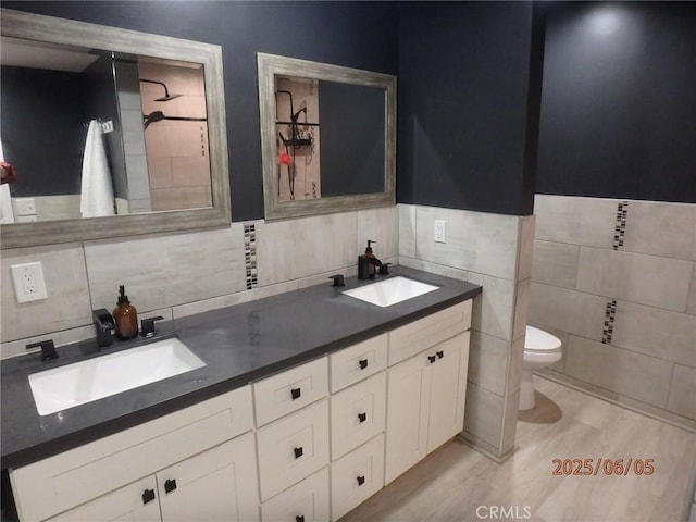 17457 Covello St, Van Nuys, CA 91406 - bathroom featuring tile walls, double vanity, toilet, and wood finished floors