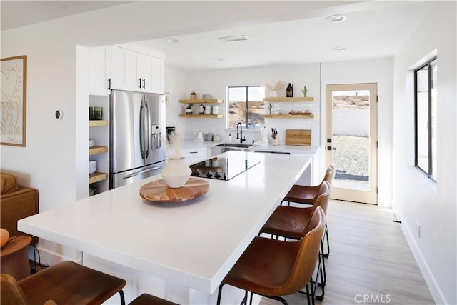 63326 Sunny Sands Dr, Joshua Tree, CA 92252 - kitchen featuring stainless steel refrigerator with ice dispenser, open shelves, a sink, black electric stovetop, and a kitchen bar