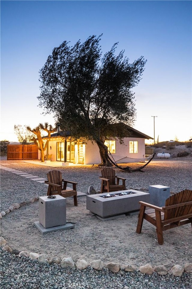 63326 Sunny Sands Dr, Joshua Tree, CA 92252 - back of property at dusk featuring an outdoor fire pit and stucco siding