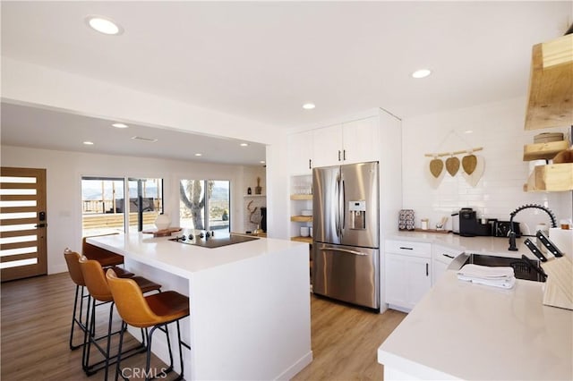 63326 Sunny Sands Dr, Joshua Tree, CA 92252 - kitchen featuring stainless steel fridge, black electric cooktop, a breakfast bar area, light wood finished floors, and a sink
