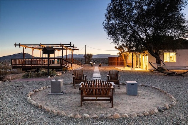 63326 Sunny Sands Dr, Joshua Tree, CA 92252 - patio terrace at dusk featuring a pergola, a deck with mountain view, a fire pit, and a patio