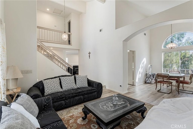 25213 Via Las Lomas, Murrieta, CA 92562 - living area featuring arched walkways, a high ceiling, wood finished floors, stairs, and a chandelier