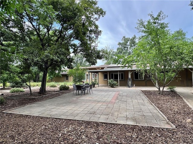 8 Geneva Ln, Chico, CA 95926 - back of house featuring roof mounted solar panels, stucco siding, and a patio area