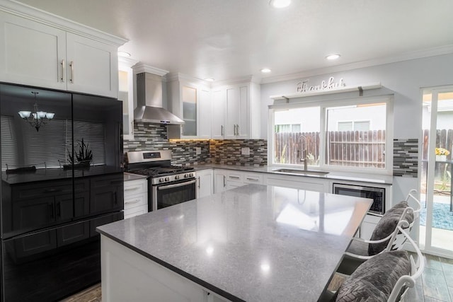 1242 Pleasant Hill St, Escondido, CA 92026 - kitchen with stainless steel appliances, wall chimney exhaust hood, tasteful backsplash, white cabinetry, and a kitchen island