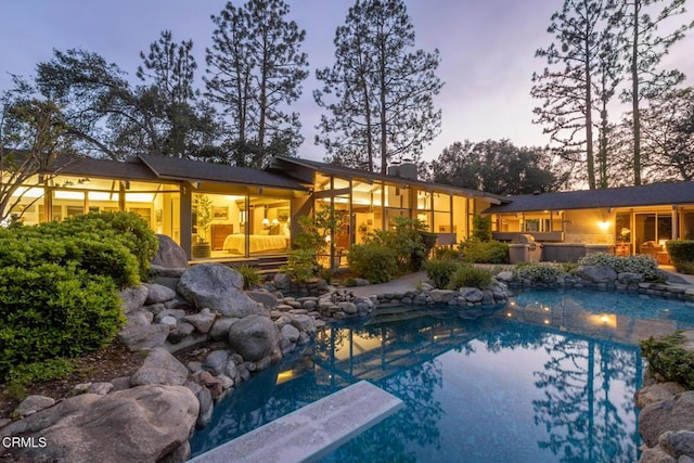 2279 Midwick Dr, Altadena, CA 91001 - back of house at dusk featuring an outdoor pool and a chimney