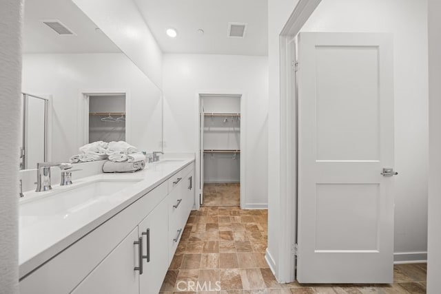 8254 Traveller St, Chino, CA 91708 - bathroom featuring a spacious closet, double vanity, stone finish flooring, baseboards, and a shower stall