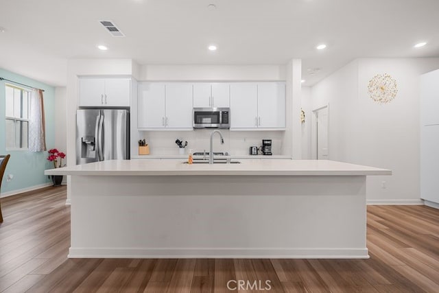 8254 Traveller St, Chino, CA 91708 - kitchen featuring appliances with stainless steel finishes, light countertops, a sink, white cabinets, and an island with sink