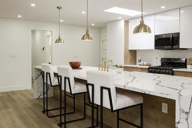 4380 Rolfe Rd, San Diego, CA 92117 - kitchen with stainless steel appliances, modern cabinets, white cabinetry, light wood finished floors, and a breakfast bar