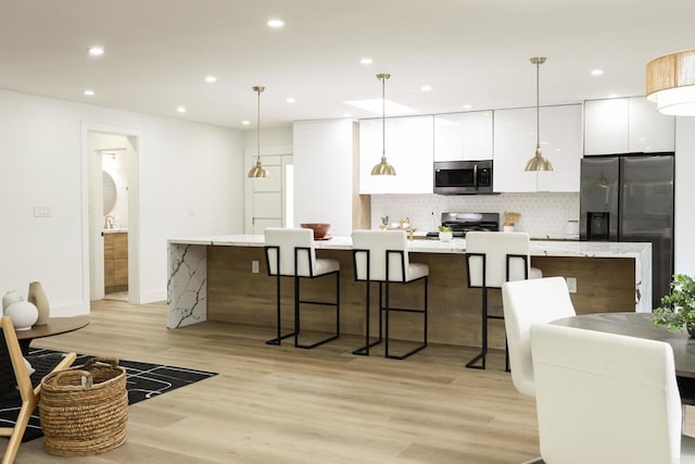 4380 Rolfe Rd, San Diego, CA 92117 - kitchen with stainless steel appliances, a spacious island, white cabinets, modern cabinets, and light wood-type flooring