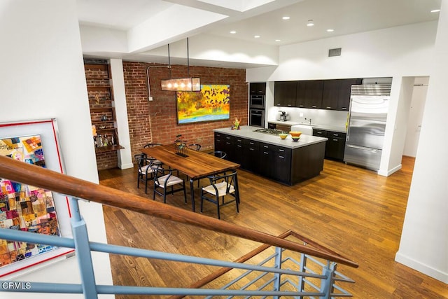 940 E 2nd St Unit 37, Los Angeles, CA 90012 - kitchen featuring appliances with stainless steel finishes, a kitchen island, dark cabinetry, light countertops, and wood finished floors