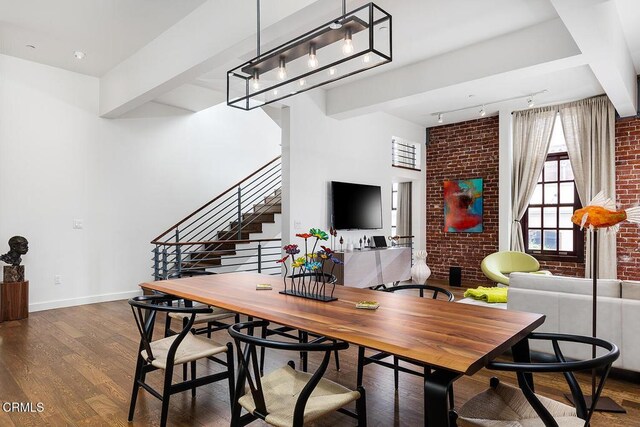 940 E 2nd St Unit 37, Los Angeles, CA 90012 - dining space with dark wood finished floors, track lighting, brick wall, stairs, and beamed ceiling