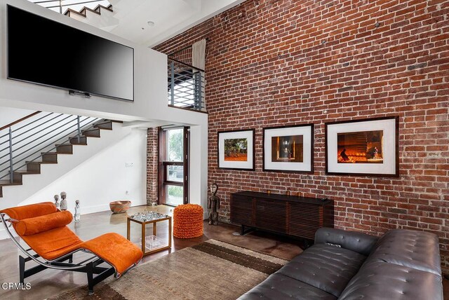 940 E 2nd St Unit 37, Los Angeles, CA 90012 - living room featuring a towering ceiling, stairway, and brick wall