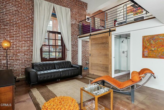 940 E 2nd St Unit 37, Los Angeles, CA 90012 - living area with a towering ceiling, a barn door, brick wall, and concrete flooring