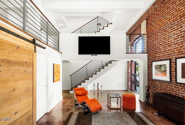 940 E 2nd St Unit 37, Los Angeles, CA 90012 - living area with stairs, a high ceiling, brick wall, concrete floors, and a barn door