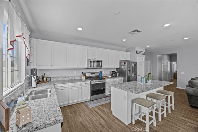 24909 Miners View Ln, Moreno Valley, CA 92557 - kitchen with stainless steel appliances, a kitchen island, white cabinets, a breakfast bar area, and recessed lighting