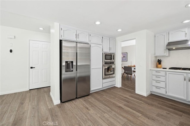 28034 Parkridge Ln, Canyon Country, CA 91387 - kitchen featuring appliances with stainless steel finishes, ventilation hood, wood finished floors, recessed lighting, and white cabinets
