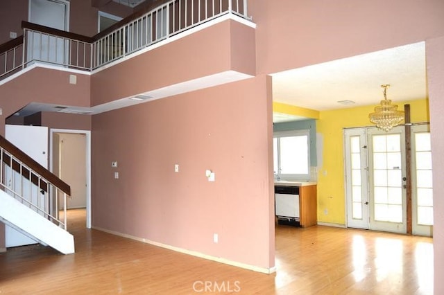 12077 Swegles Ln, Moreno Valley, CA 92557 - unfurnished living room featuring stairway, wood finished floors, a chandelier, and a towering ceiling