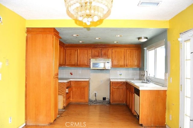 12077 Swegles Ln, Moreno Valley, CA 92557 - kitchen with white microwave, a sink, light wood-style floors, backsplash, and a chandelier