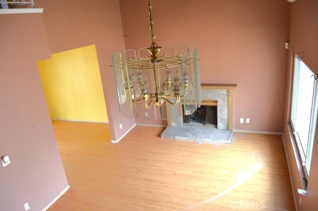 12077 Swegles Ln, Moreno Valley, CA 92557 - unfurnished living room with wood finished floors, a towering ceiling, baseboards, a chandelier, and a fireplace