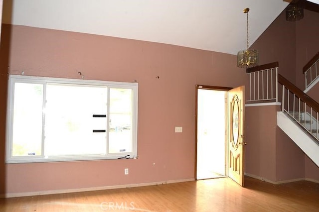 12077 Swegles Ln, Moreno Valley, CA 92557 - unfurnished living room featuring a chandelier, wood finished floors, stairway, vaulted ceiling, and baseboards