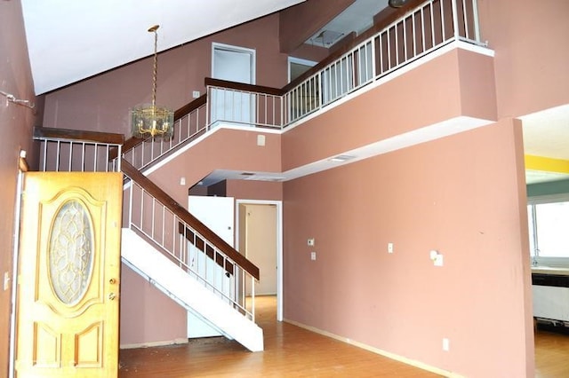 12077 Swegles Ln, Moreno Valley, CA 92557 - staircase with a towering ceiling, wood finished floors, a chandelier, and baseboards