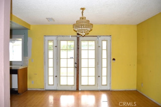 12077 Swegles Ln, Moreno Valley, CA 92557 - entryway with wood finished floors, a chandelier, healthy amount of natural light, baseboards, and a textured ceiling