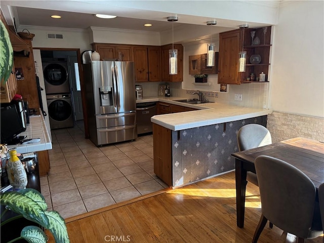 357 Cumberland Rd, Glendale, CA 91202 - kitchen with appliances with stainless steel finishes, stacked washer / dryer, a sink, ornamental molding, and tile countertops