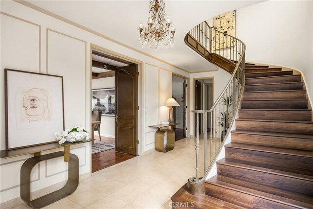 508 Evening Star Ln, Newport Beach, CA 92660 - foyer entrance featuring a chandelier, stairs, a decorative wall, light tile patterned flooring, and ornamental molding