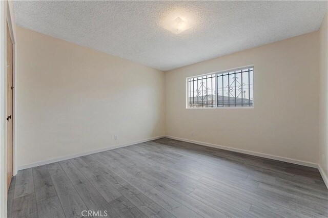 4820 Eagle St, Los Angeles, CA 90022 - empty room with a textured ceiling, wood finished floors, and baseboards