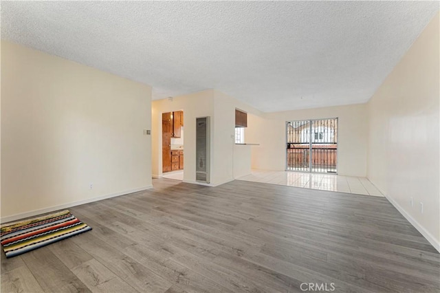 4820 Eagle St, Los Angeles, CA 90022 - unfurnished living room featuring wood finished floors, a textured ceiling, and baseboards
