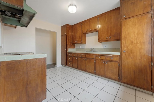 4820 Eagle St, Los Angeles, CA 90022 - kitchen with extractor fan, a sink, brown cabinetry, and light tile patterned floors