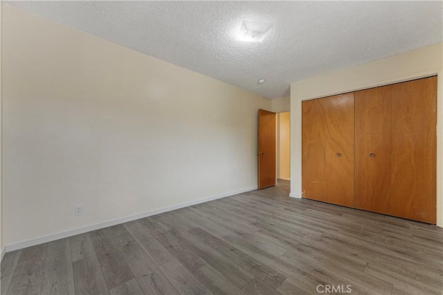 4820 Eagle St, Los Angeles, CA 90022 - unfurnished bedroom with a textured ceiling, wood finished floors, a closet, and baseboards