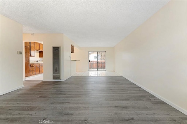 4820 Eagle St, Los Angeles, CA 90022 - unfurnished living room featuring a heating unit, wood finished floors, a textured ceiling, baseboards, and a sink