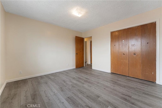 4820 Eagle St, Los Angeles, CA 90022 - unfurnished bedroom featuring wood finished floors, a textured ceiling, baseboards, and a closet