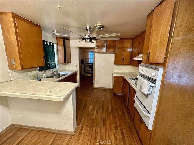 1947 Palm Ave, Monterey Park, CA 91755 - kitchen with white oven, brown cabinetry, a sink, a peninsula, and dark wood-style floors