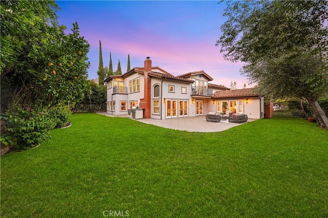 25811 Jamon Ln, Mission Viejo, CA 92691 - back of property at dusk with a balcony, a chimney, french doors, a patio area, and stucco siding