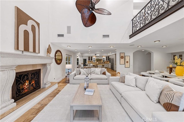25811 Jamon Ln, Mission Viejo, CA 92691 - living area with a towering ceiling, ceiling fan, arched walkways, a warm lit fireplace, and recessed lighting