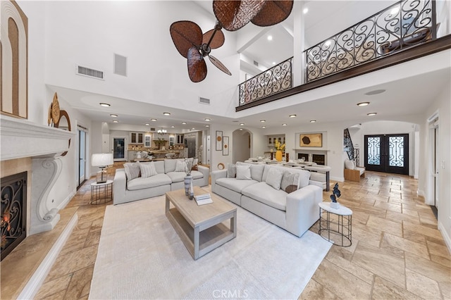 25811 Jamon Ln, Mission Viejo, CA 92691 - living room featuring arched walkways, a high ceiling, stone tile flooring, a ceiling fan, and a high end fireplace