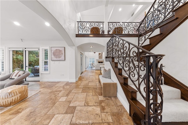 25811 Jamon Ln, Mission Viejo, CA 92691 - staircase featuring stone tile floors, arched walkways, a high ceiling, recessed lighting, and beam ceiling