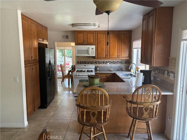 2770 Cole Ave, Highland, CA 92346 - kitchen with white appliances, a sink, a peninsula, brown cabinetry, and tasteful backsplash