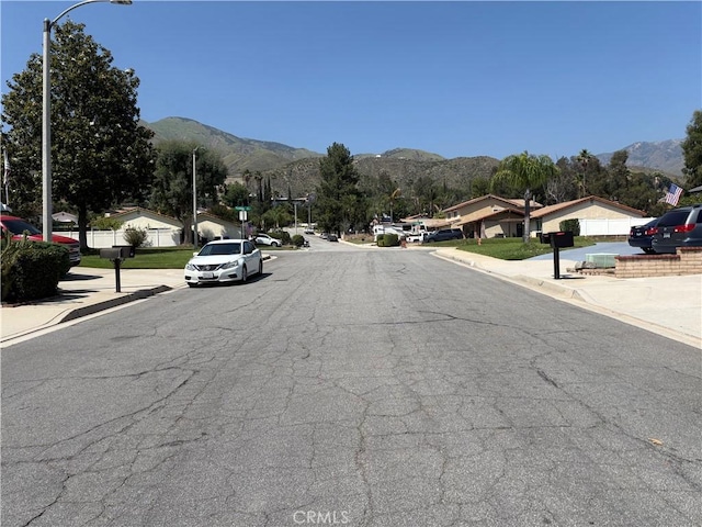 2770 Cole Ave, Highland, CA 92346 - view of asphalt street featuring a mountain view, curbs, and street lighting