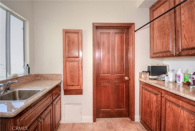 8140 Del Ct, Phelan, CA 92371 - kitchen featuring a sink, brown cabinetry, baseboards, light stone countertops, and light tile patterned flooring