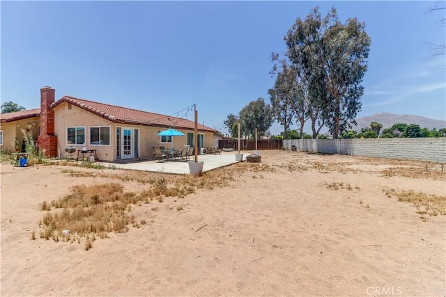 12642 Gorham St, Moreno Valley, CA 92553 - rear view of property featuring a patio area, a tiled roof, a fenced backyard, stucco siding, and a chimney
