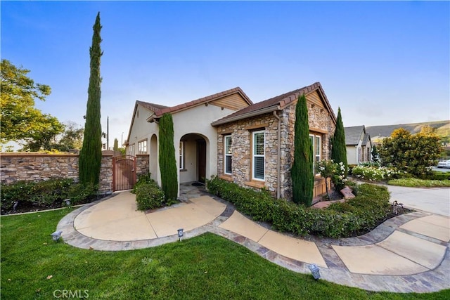 20010 Livorno Ln, Yorba Linda, CA 92886 - mediterranean / spanish home with a gate, stone siding, stucco siding, a front lawn, and a tile roof