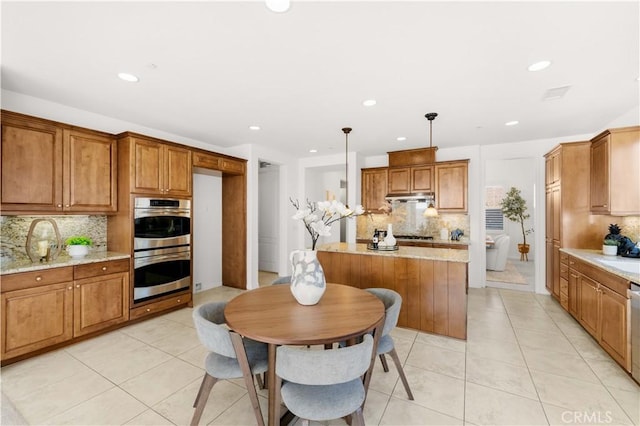 20010 Livorno Ln, Yorba Linda, CA 92886 - kitchen with stainless steel appliances, under cabinet range hood, decorative backsplash, brown cabinetry, and light tile patterned floors