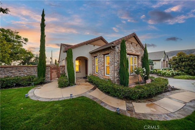 20010 Livorno Ln, Yorba Linda, CA 92886 - view of front of home featuring a gate, stone siding, a front yard, stucco siding, and a tile roof
