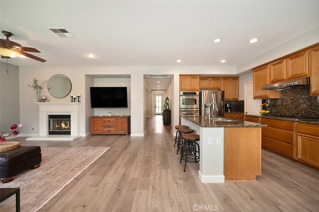 28978 Williston Ct, Temecula, CA 92591 - kitchen featuring stainless steel appliances, under cabinet range hood, a kitchen bar, dark stone countertops, and ceiling fan