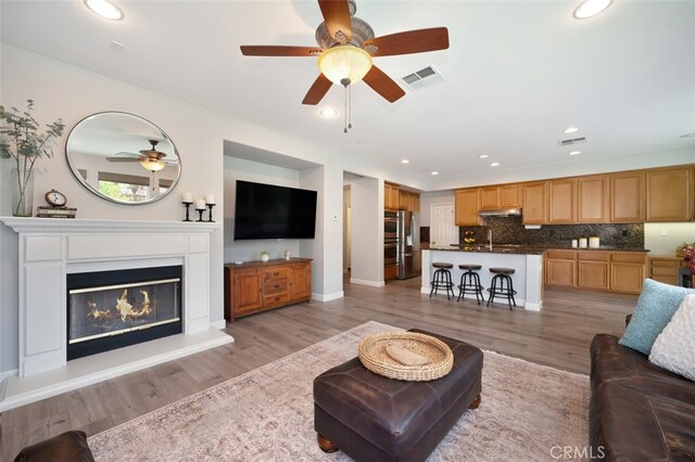 28978 Williston Ct, Temecula, CA 92591 - living area with ceiling fan, light wood finished floors, recessed lighting, and a glass covered fireplace