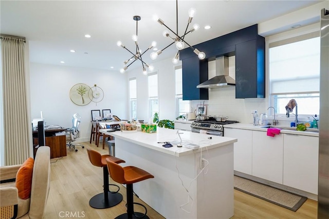 137 Saint Francis St Unit A, San Gabriel, CA 91776 - kitchen featuring wall chimney range hood, a center island, light wood-style flooring, light countertops, and modern cabinets