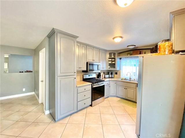 743 N Beechwood Ave, Rialto, CA 92376 - kitchen featuring stainless steel appliances, light tile patterned floors, light countertops, gray cabinetry, and glass insert cabinets